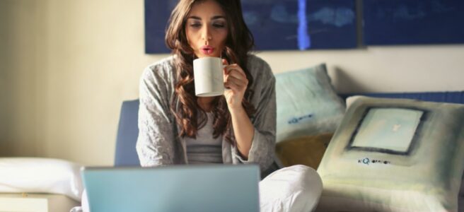 woman taking coffee while using laptop